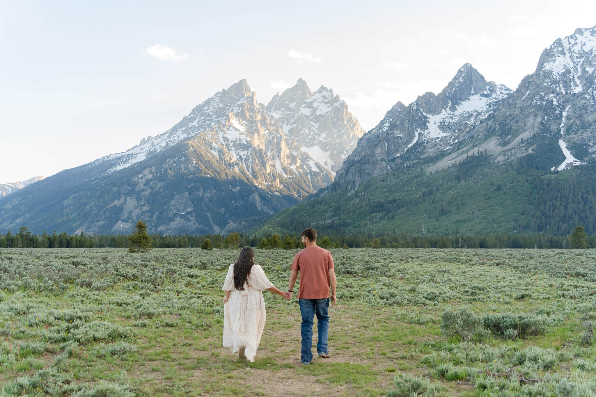 Couple walking in the shadow of the huge Grand Teton range