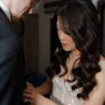 bride helps get her groom's jacket on as they get ready for their enchanted rock elopement