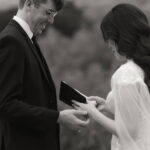 groom softly touches his brides hands while she reads her vows during their Intimate elopement ceremony on a secluded trail at Enchanted Rock State Park