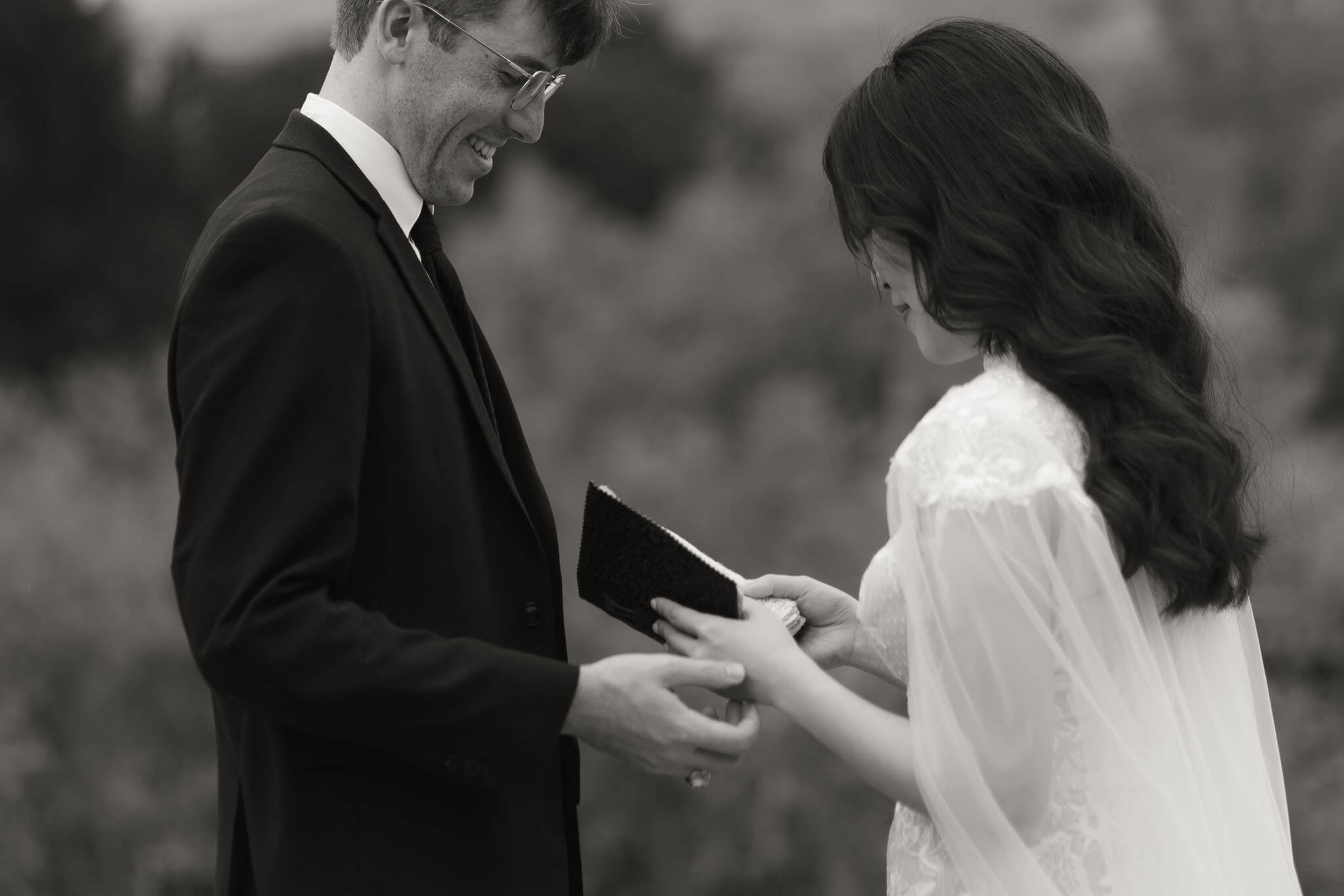 groom softly touches his brides hands while she reads her vows during their Intimate elopement ceremony on a secluded trail at Enchanted Rock State Park