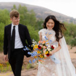 Bride and groom holding hands with Enchanted Rock granite dome in the background