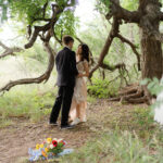 Bride and groom sharing first dance under a large tree near Enchanted Rock
