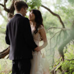 Bride and groom sharing first dance under a large tree near Enchanted Rock