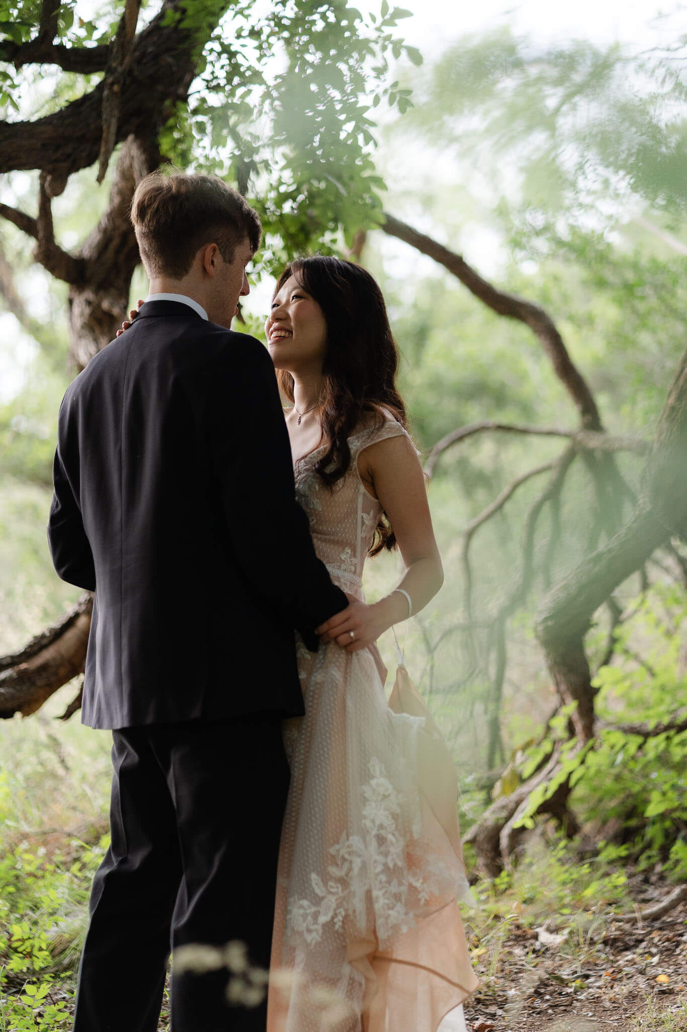 Bride and groom sharing first dance under a large tree near Enchanted Rock