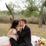 couple kissing on a picnic blanket during their romantic alternative elopement celebration