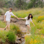 Wildflowers blooming near Enchanted Rock with couple crossing a small creek bed