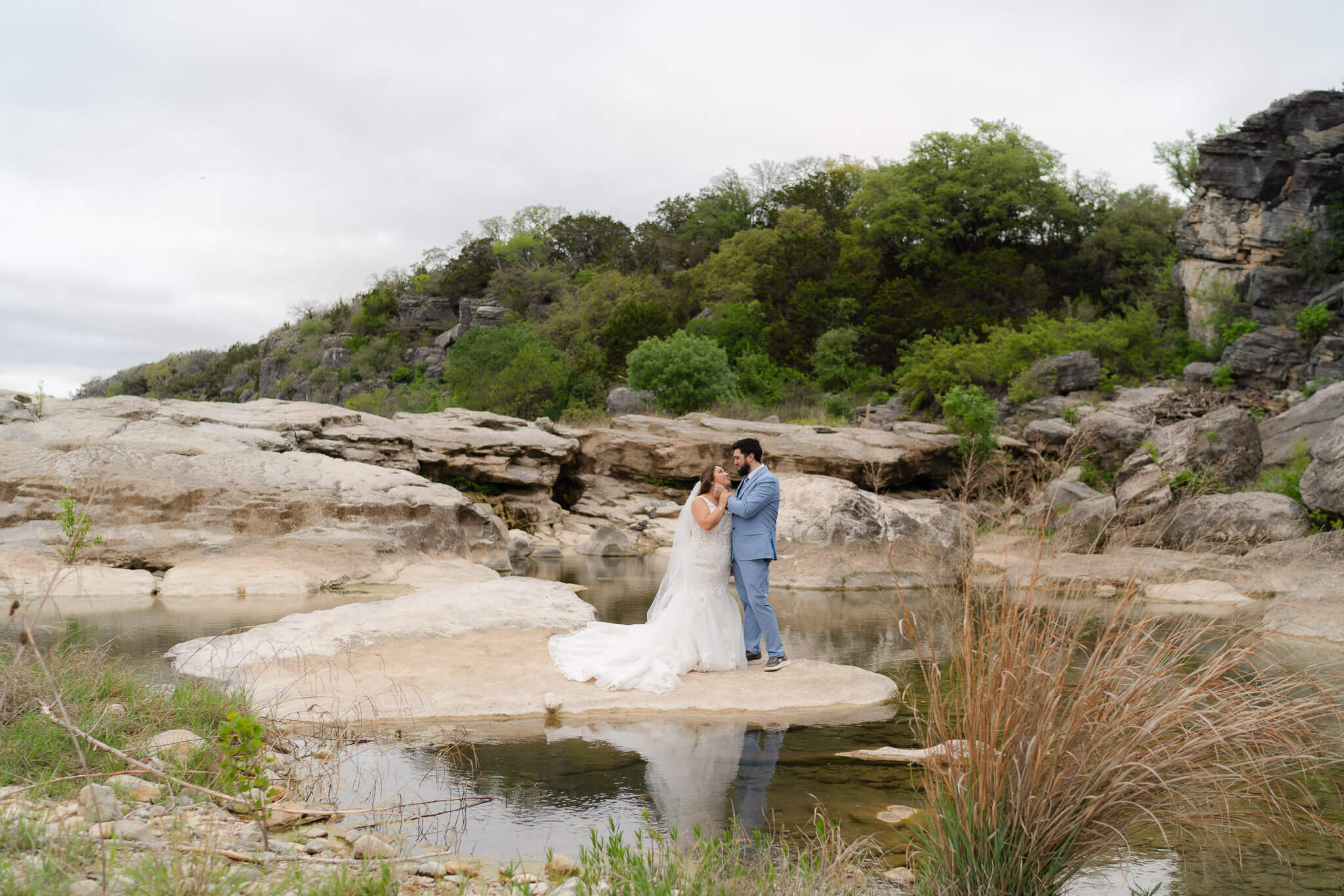 Bride and groom stand together on a small island in a river