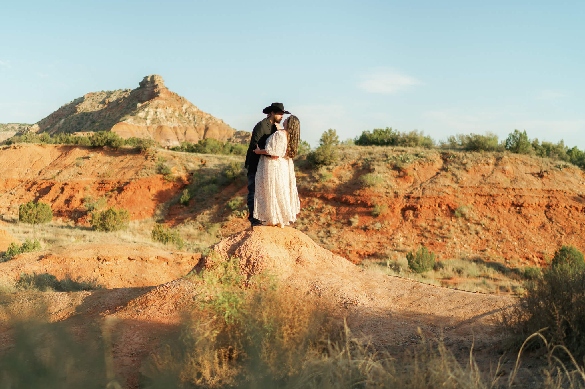 Couple placed on a red rock embracing together How to Elope, find a photographer who will capture your story