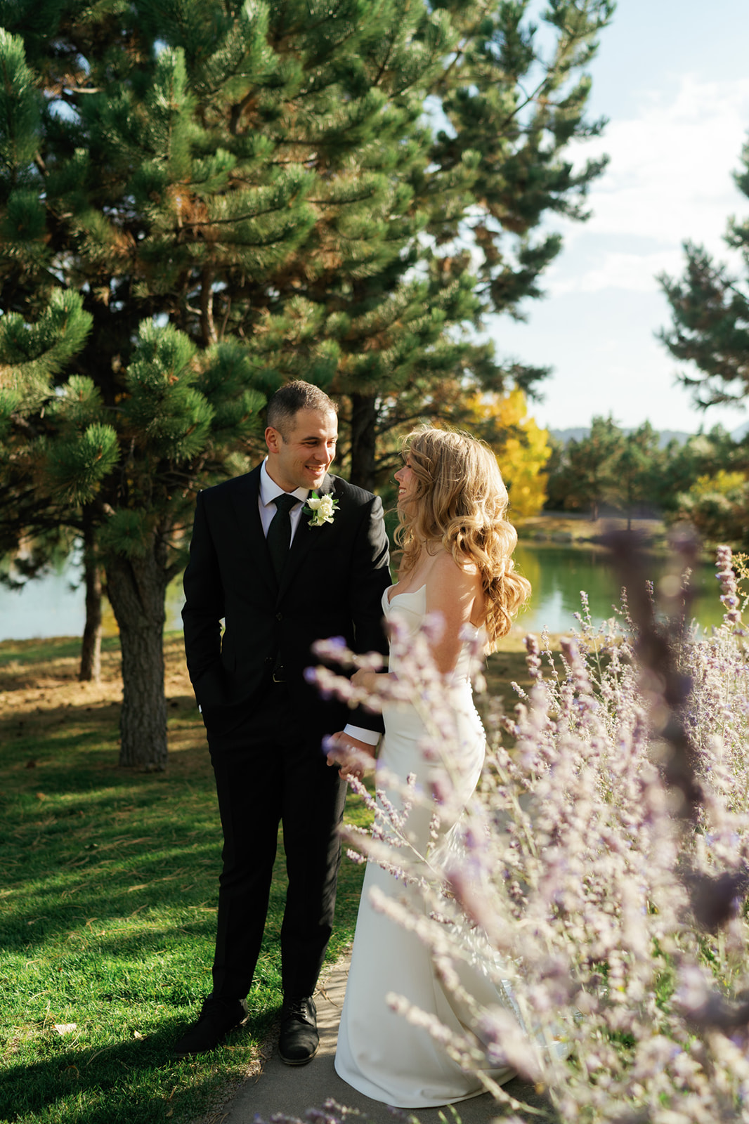 A bride and groom smile at each other while walking hand in hand through a garden while Eloping in Montana