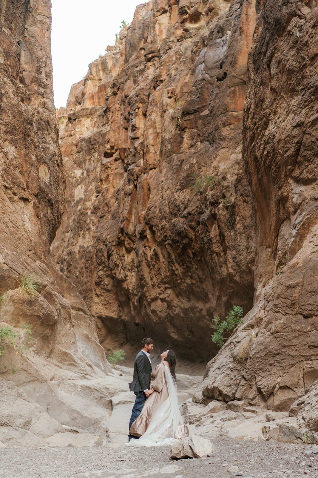 Newlyweds laugh together while holding hands close in a deep canyon during their Utah Elopement