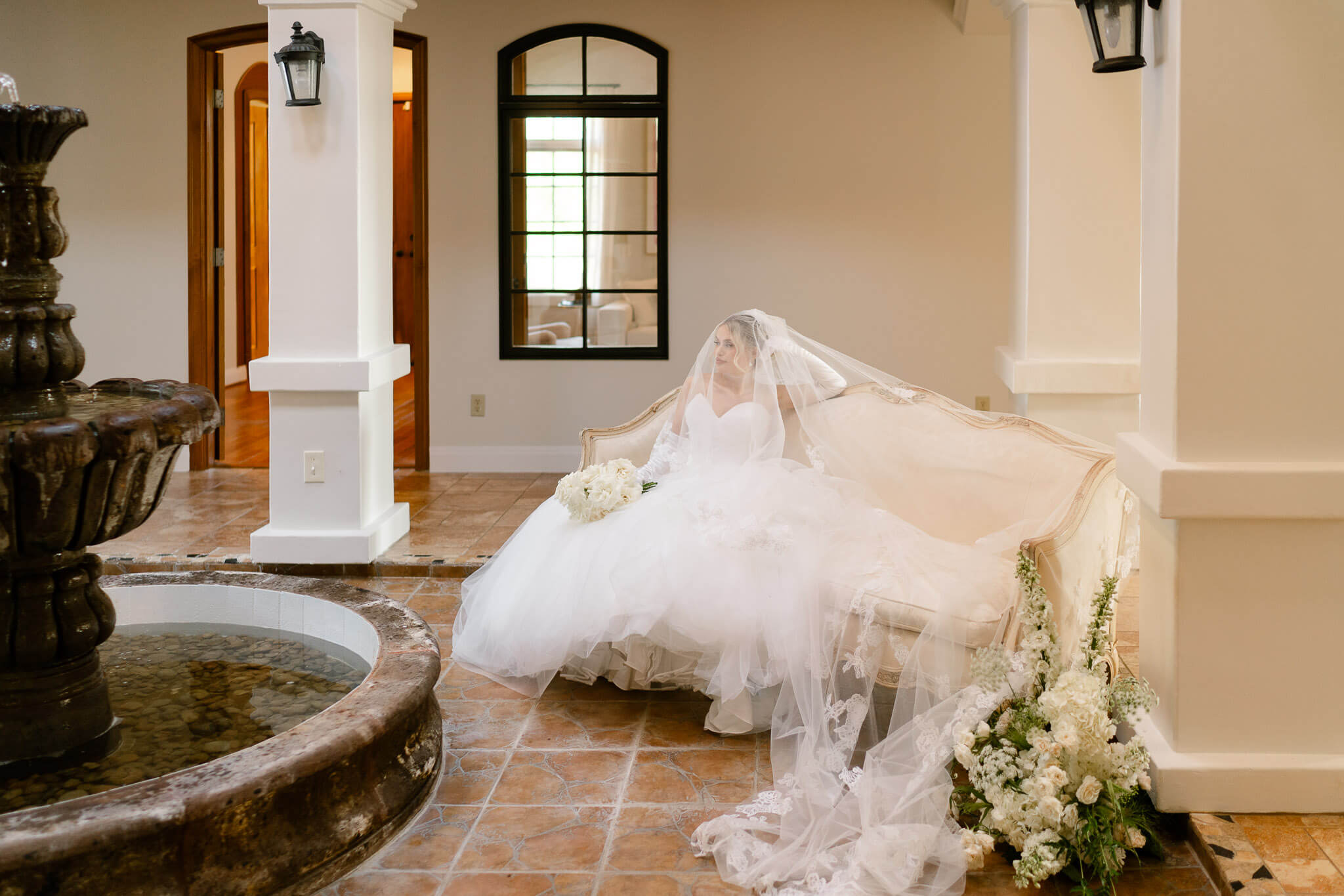 Bride lounging on a couch in a historic bridal suite at a Austin wedding venues