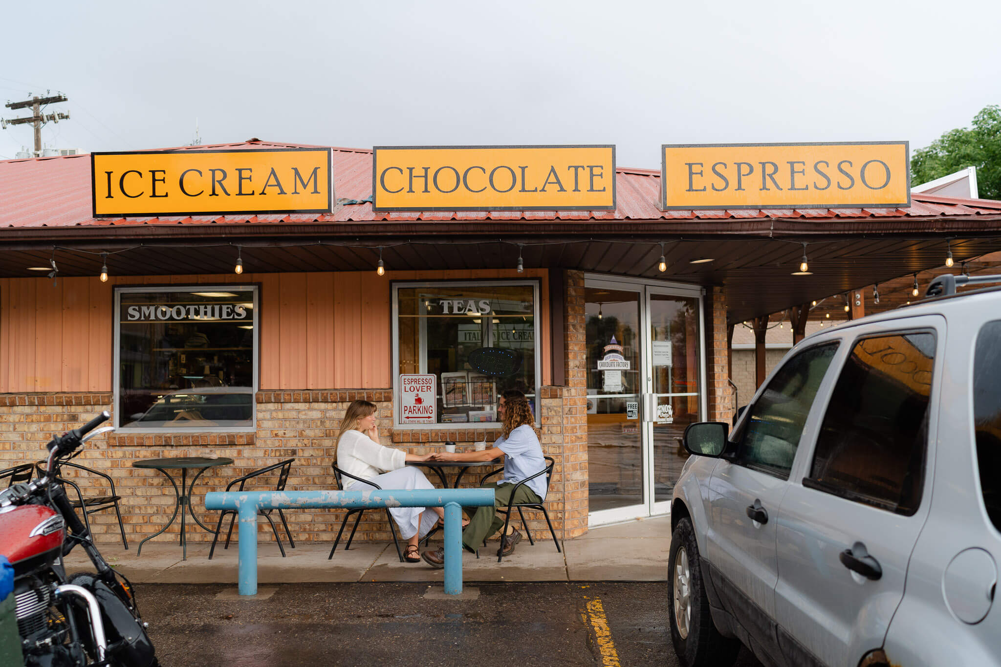 Couple sipping coffee on the patio of a Moab coffee shop on a rainy wedding day before their Dead horse point wedding