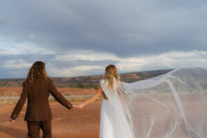 bride and groom look off into the distance as her veil flys