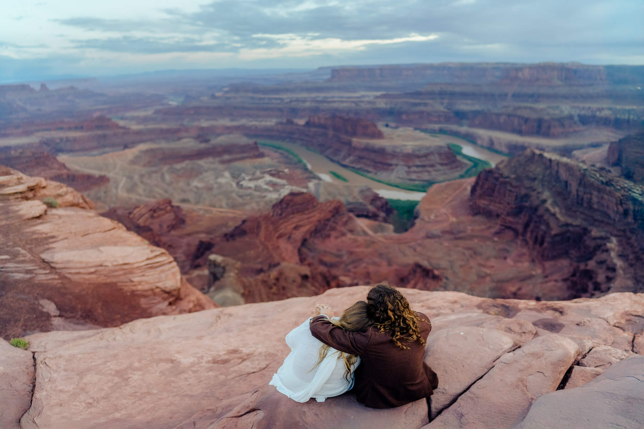 Couple resting on the edge of Dead Horse Point with expansive canyon views