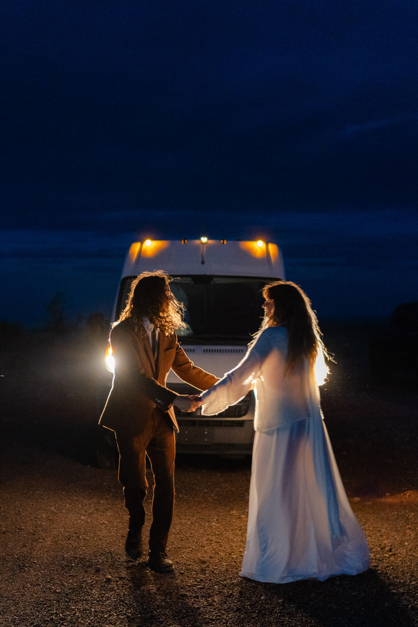 couple shares a dance in the headlights of their van