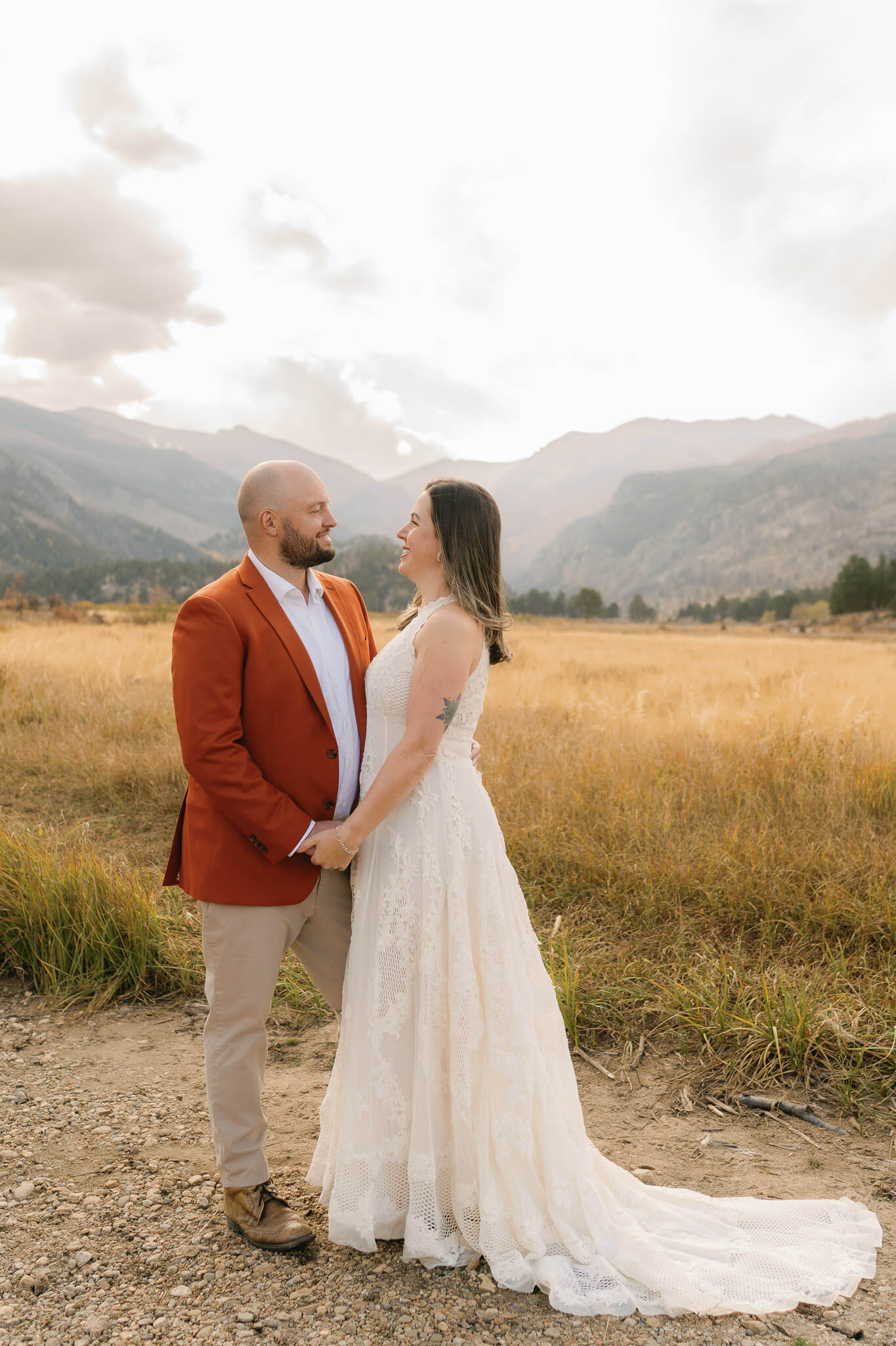 couple standing together in a dry creek, his burnt orange suit jacket fit the fall colors
