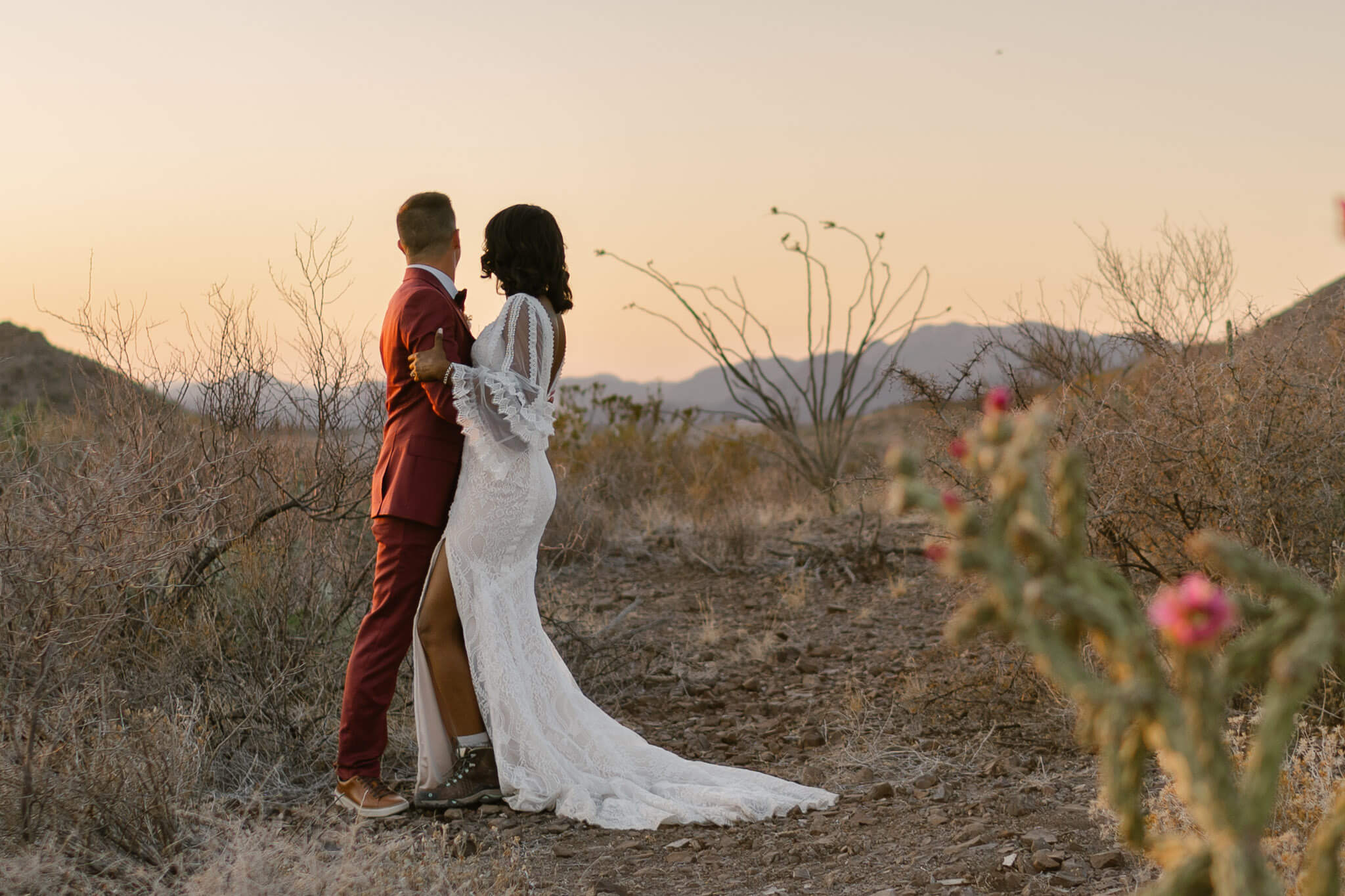 couple standing in the desert in their elopement outfits which included hiking boots