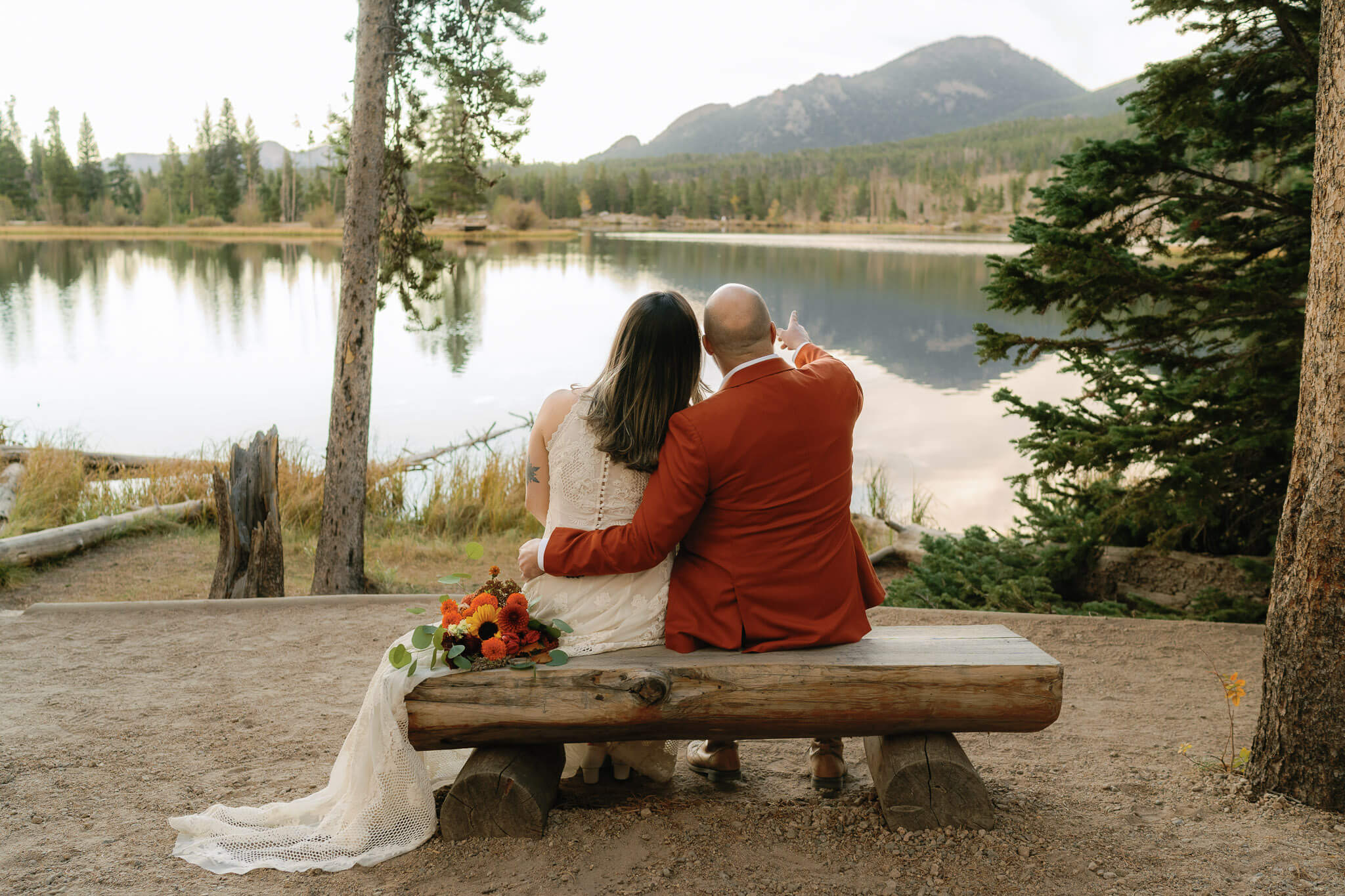couple takes in the Colorado mountain view on a waterside bench