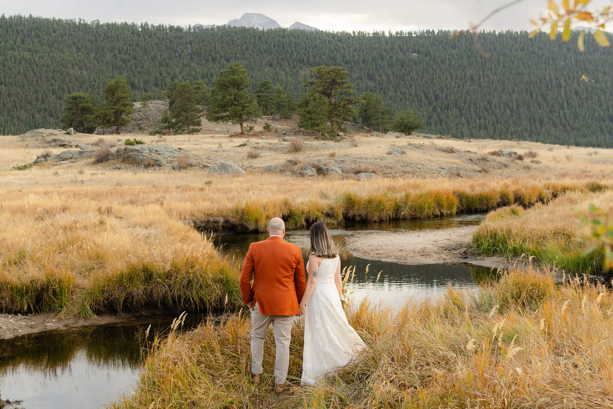 couple stands beside a quite stream on their Pagosa springs elopement day