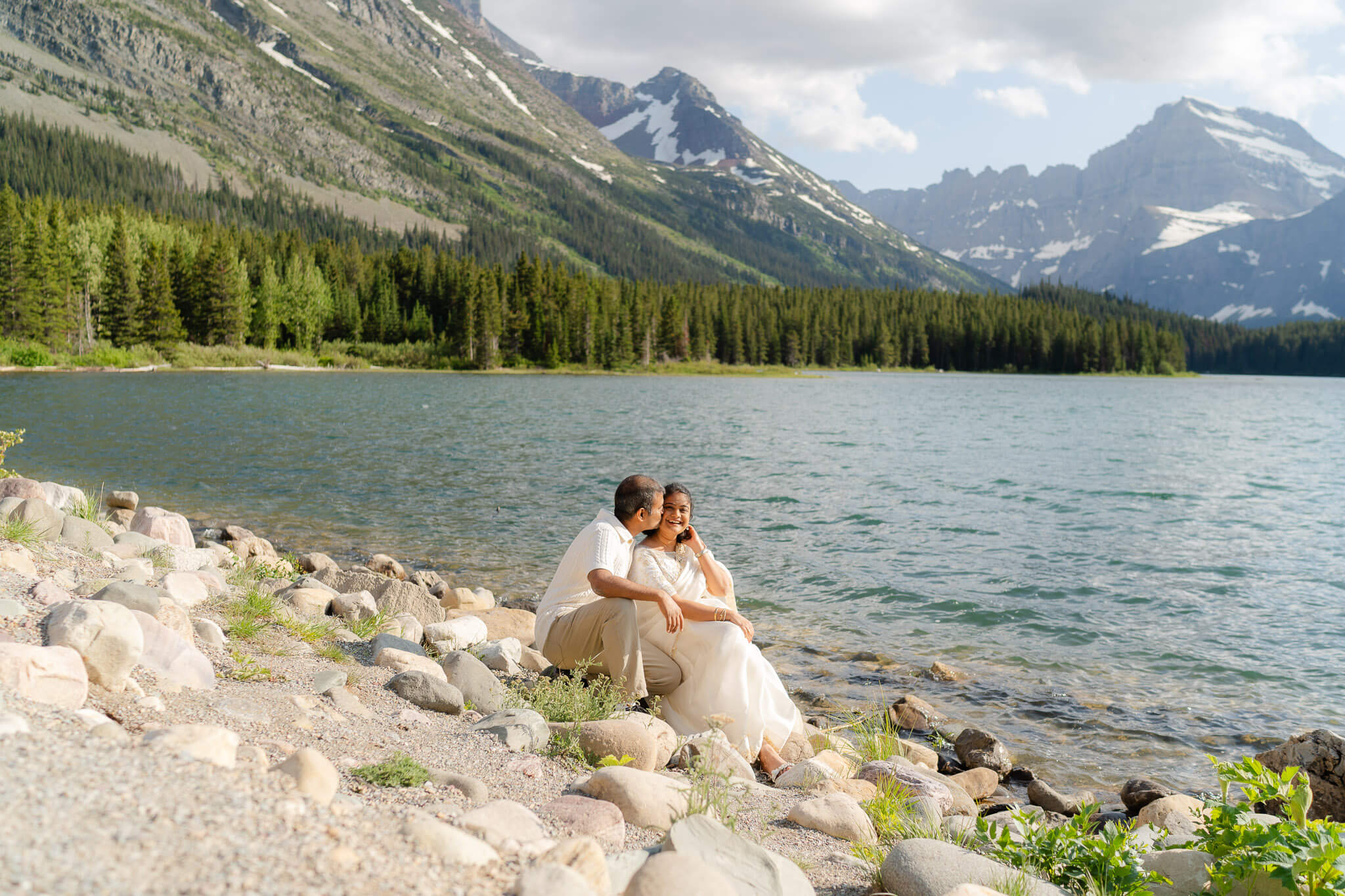 Couple sitting at a blue lake in GNP one of the best Places to elope in Montana