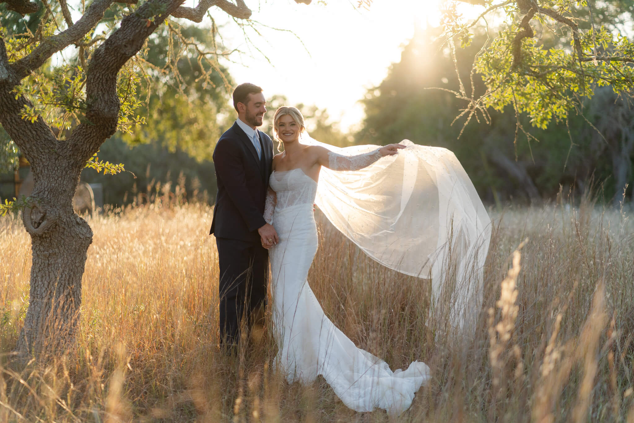 Couple stands in golden grass at sunset at their Texas Hill Country Wedding Venues