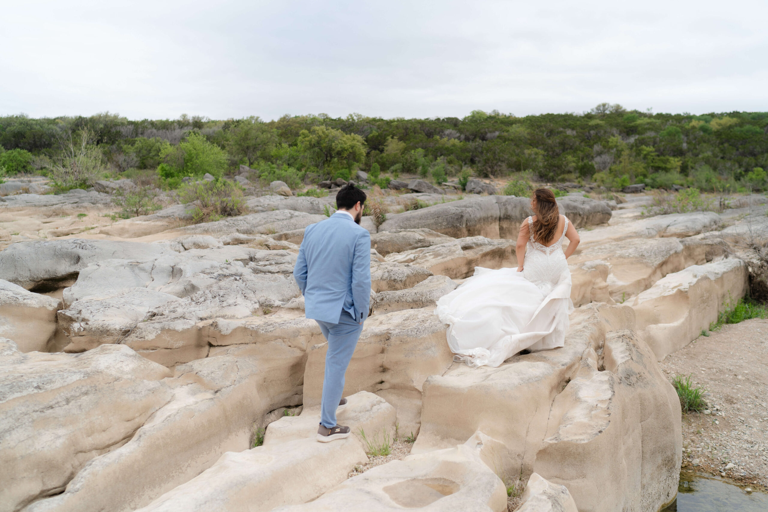 Couple navigating a rock ledge during their elopement at Pedernales Falls, a Texas Hill Country elopement destination