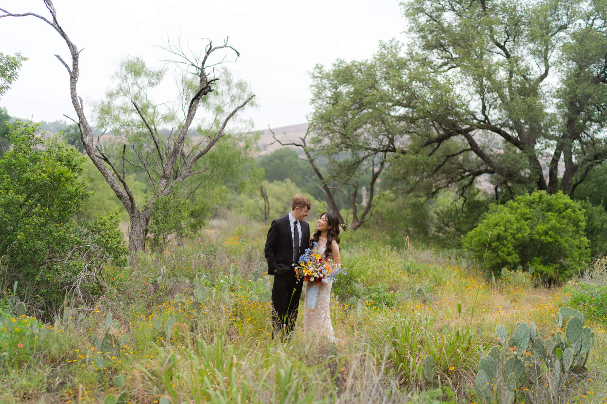 bride and groom standing amidst wildflowers as they elope in Texas