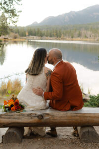 groom kisses his bride on the cheek with Colorado lake behind them