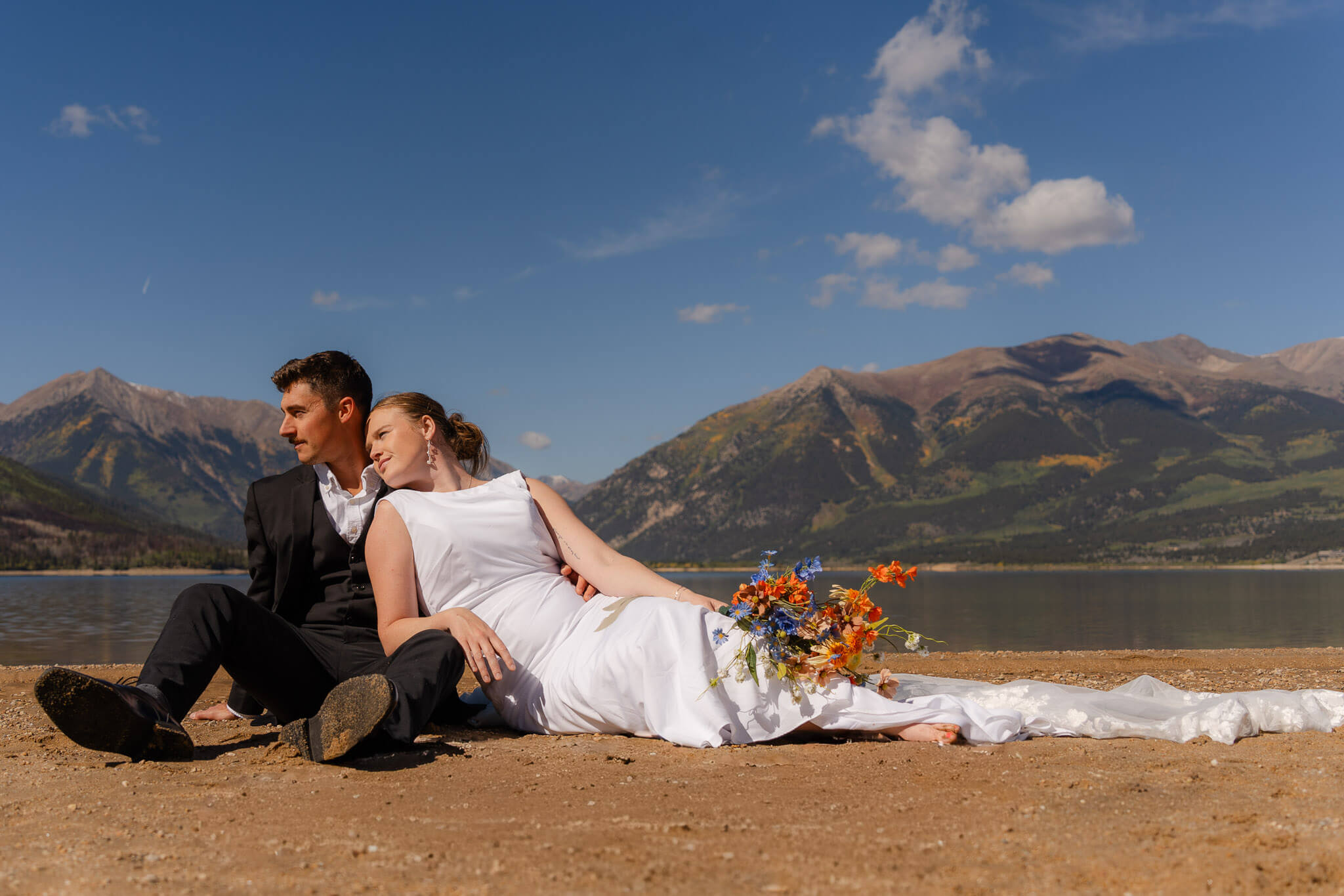 a bride and groom sitting together in the sunrise with the Colorado Mountains behind them