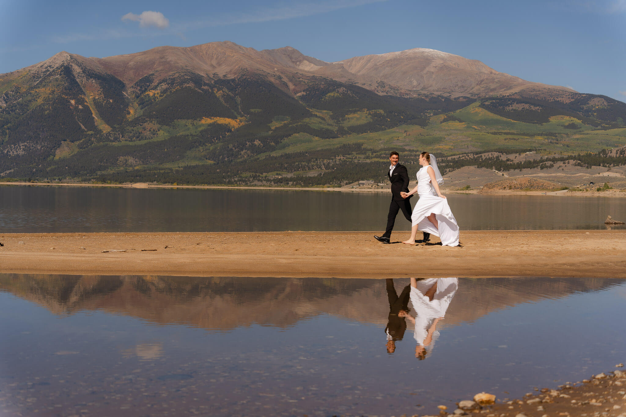 couple running along a lakeside at Twin Lakes during their elopement