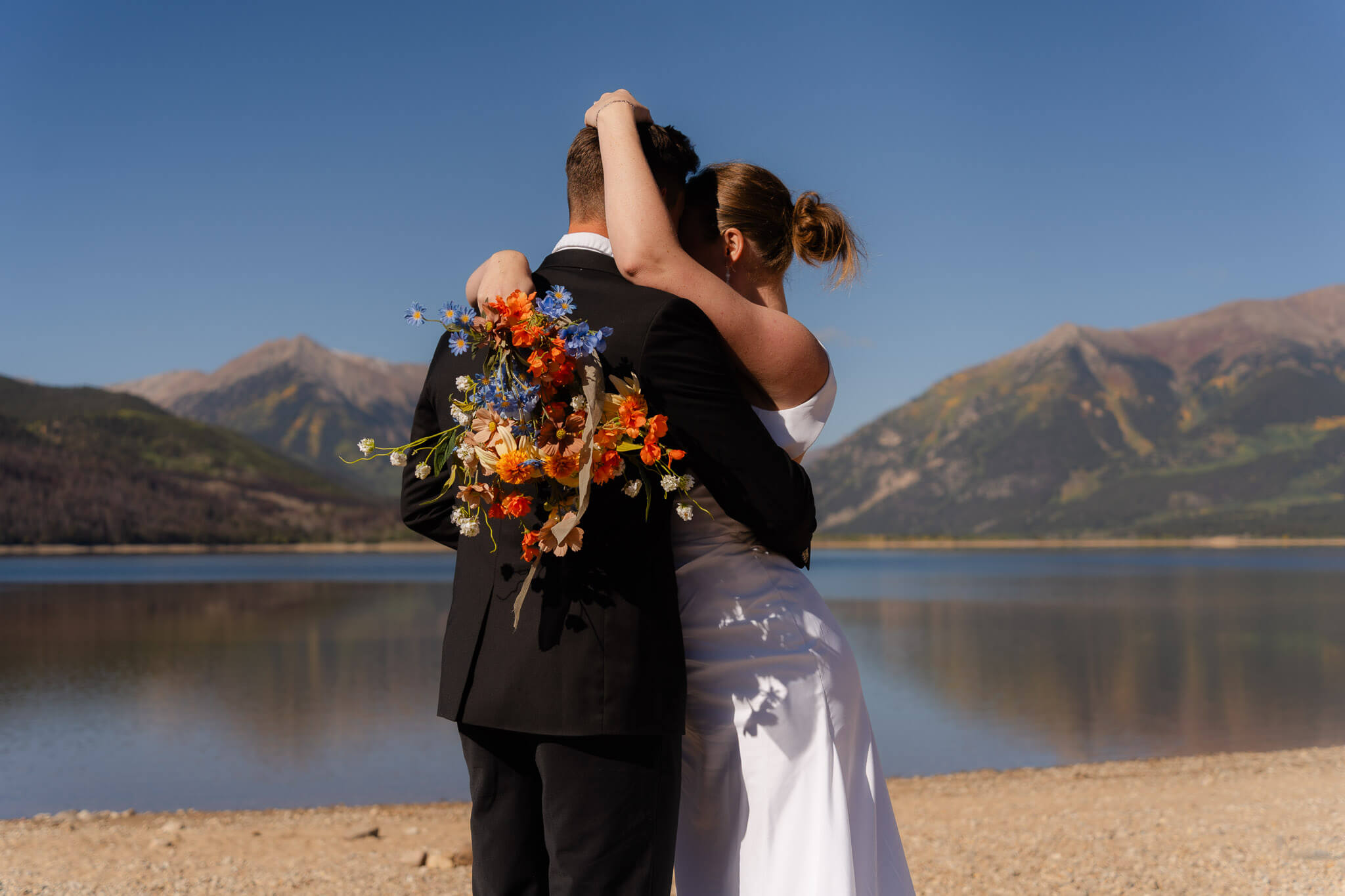 couple holding each other with the mountains behind them