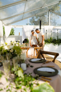 Texas couple looking at their reception details at their tropical green wedding, bride wearing a short glittering dress in the sunlight for luxe, nostalgic green wedding inspiration.