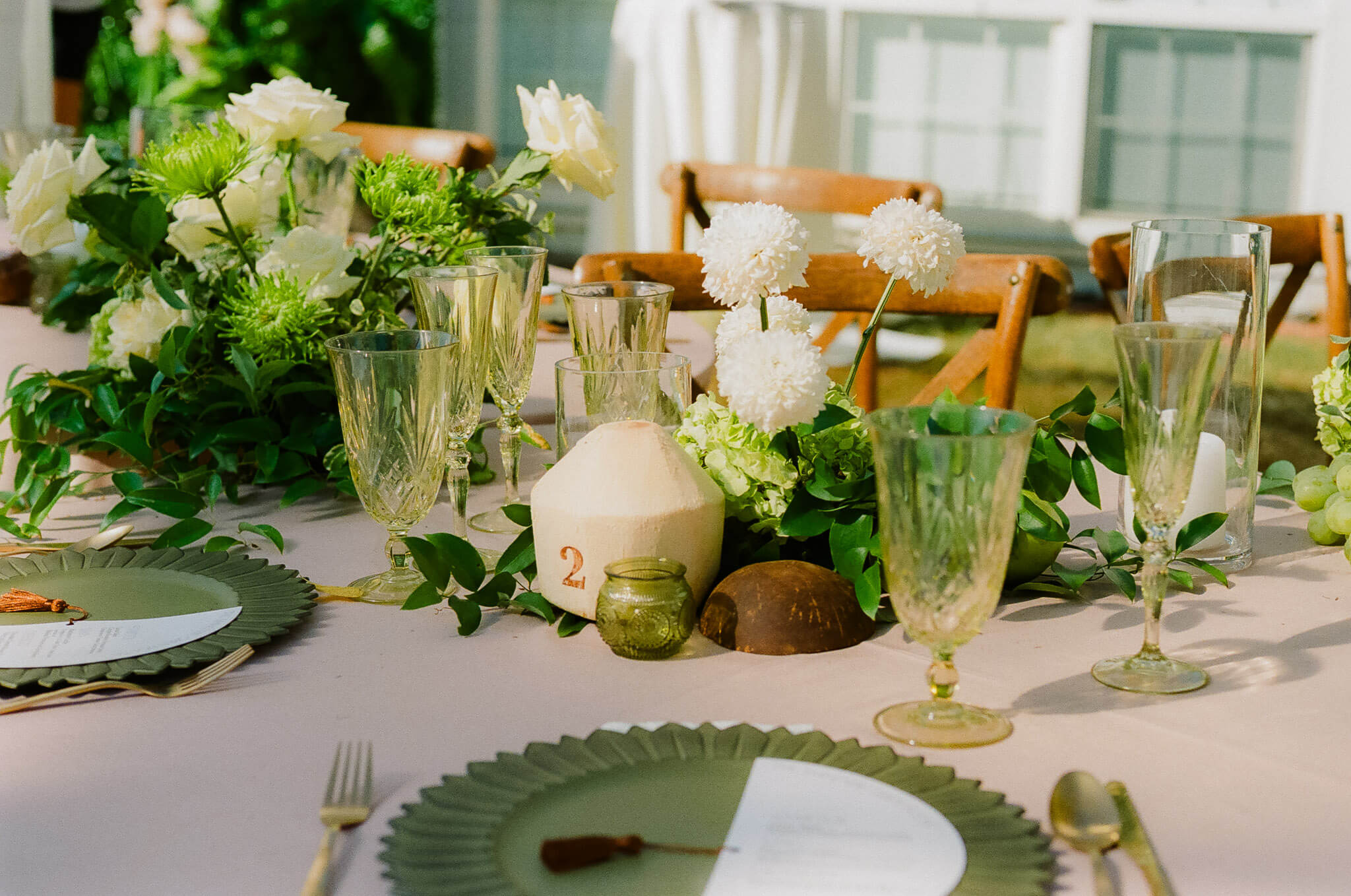 Lush green wedding reception table with coconuts, layered greenery, and vintage green glassware for Havana Nights inspired green wedding inspiration.
