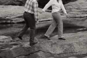 couple walking across a waterfall at their Texas engagement photos