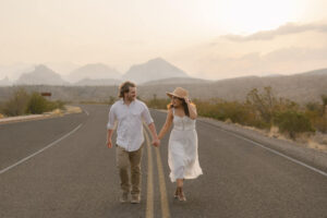 couple running on the road during their roadtrip themed texas engagement photos in Big Bend